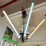 Adjustable-angle LED tubular chandelier with multi-directional arms suspended in a showroom, featuring warm and cool light tubes for modern architectural lighting