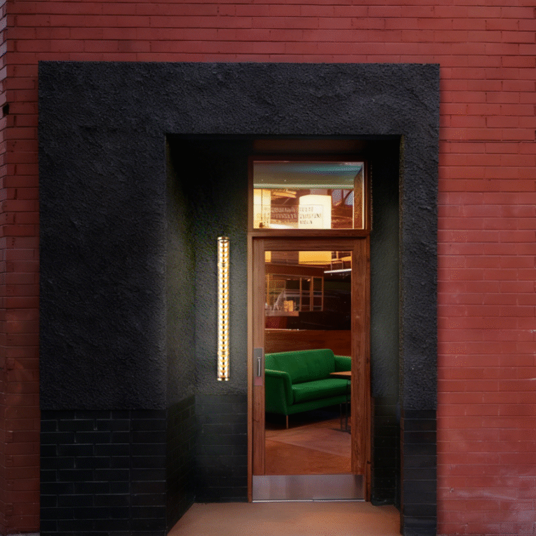 Architectural tubular wall light installed beside entrance door in commercial exterior facade