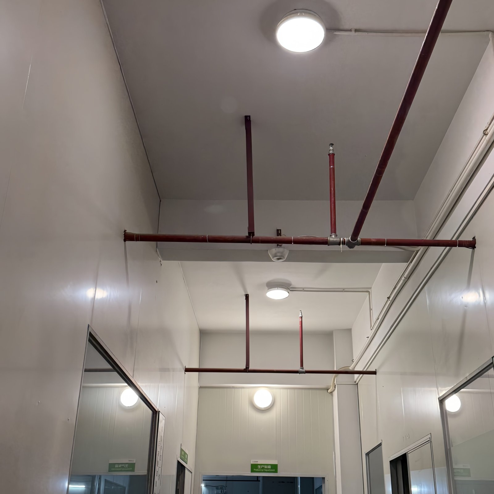 Home IP65 LED ceiling lights installed in industrial service corridor with exposed piping, providing durable and reliable lighting for technical areas